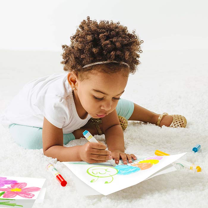 Young girl confidently coloring with crayola color wonder mess free markers on a white carpet